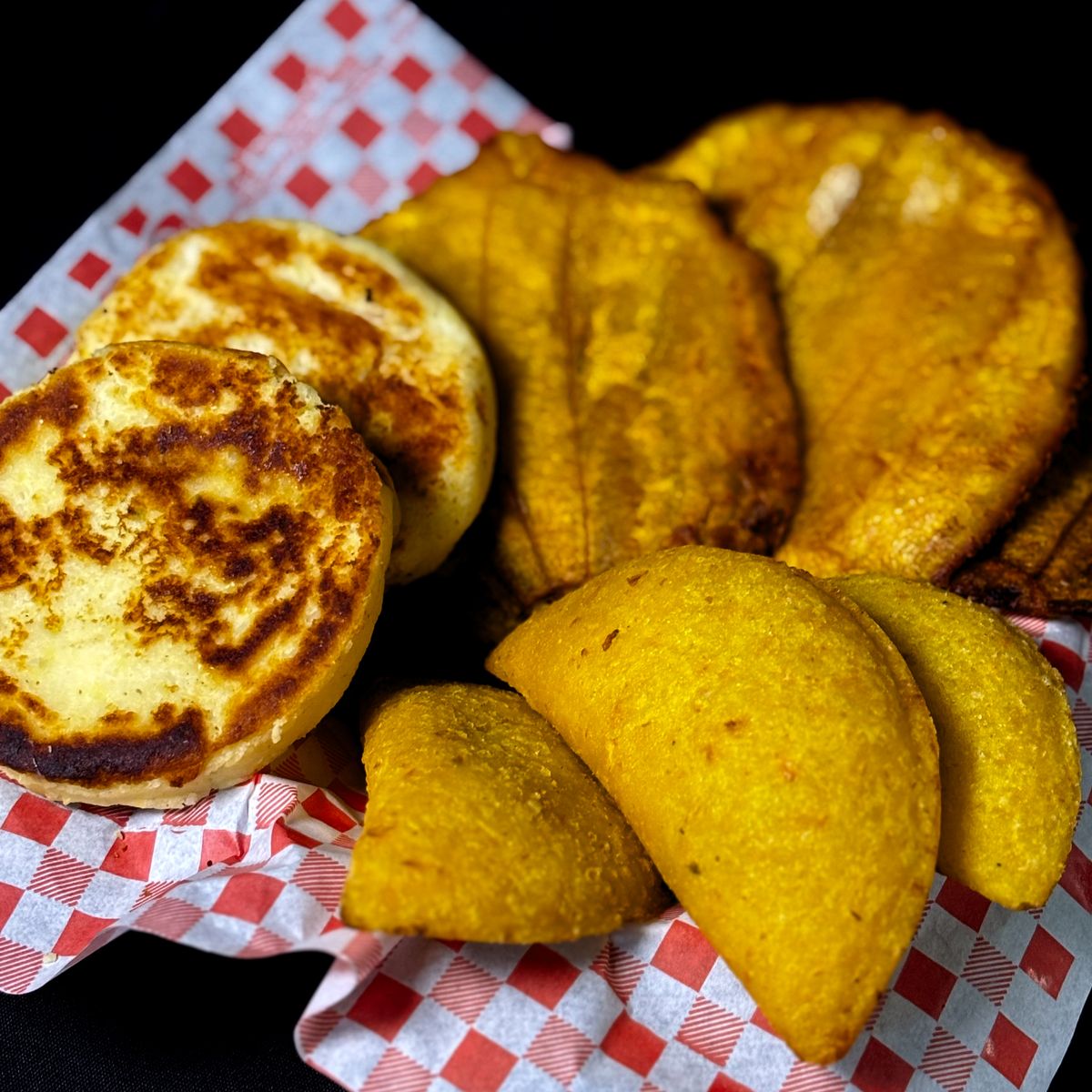 Arepas quesudas artesanales doradas junto a patacones y empanadas